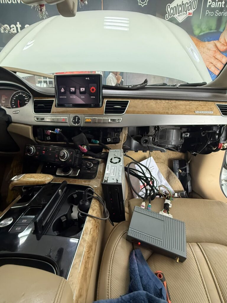 Weiss multimedia interface module wired into the dashboard of a 2012 Audi A8 during wireless CarPlay installation at Weiss Auto Concept Dubai