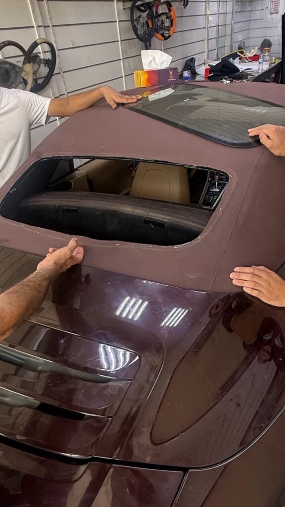 Technicians installing the rear glass into the Porsche 911 soft top in Dubai